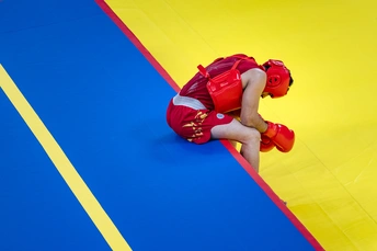 一个穿红衣服的年轻孩子在垫子上与摔跤手比赛