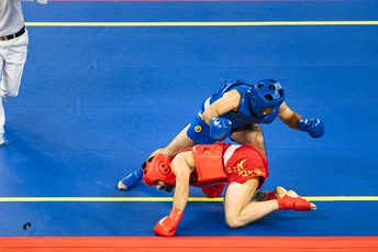 摔跤手在垫子上与一名男子摔跤