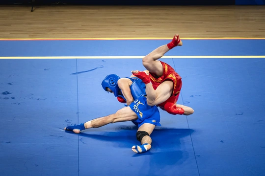 摔跤手在蓝色的垫子上与一个人摔跤