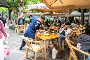 室外餐厅 有许多桌子、椅子、遮阳伞 人们在这里用餐、拍照。