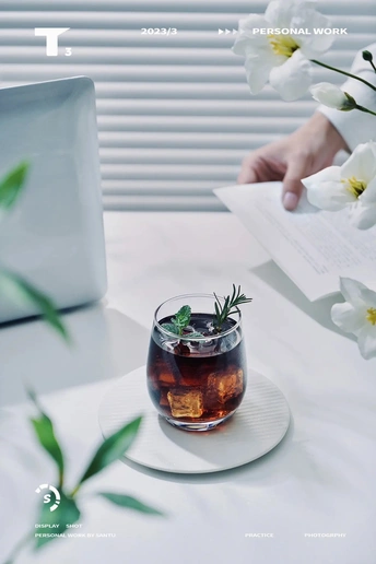 一个人坐在桌子旁 笔记本电脑、茶杯和插着花的白盘子。