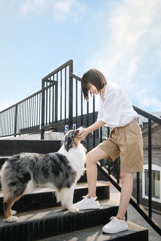 一个站在一些台阶上的女人和一只狗