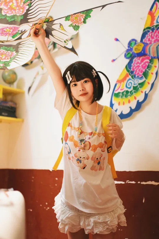 一个穿着白色连衣裙的小女孩拿着带蝴蝶的雨伞