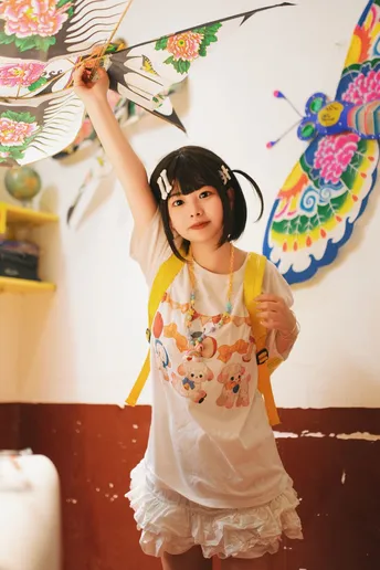 一个穿着白色连衣裙的小女孩拿着带蝴蝶的雨伞