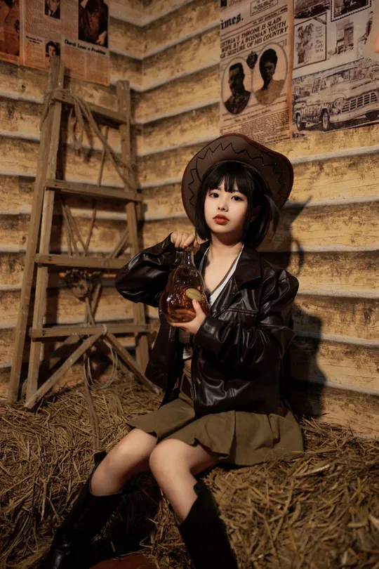 一个穿着黑色衣服的小女孩在谷仓里拿着一个小洋娃娃