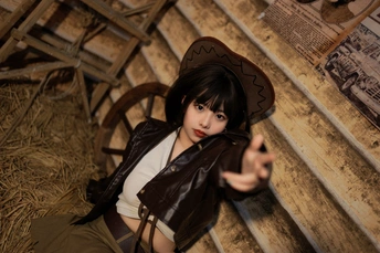 一个戴帽子和持枪的年轻女子在谷仓中摆姿势