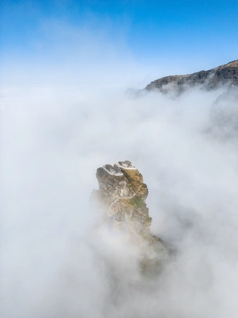a rock in a sea of clouds and fog