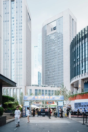 城市中的人们正在走动和骑着滑板车 周围有高大的建筑。