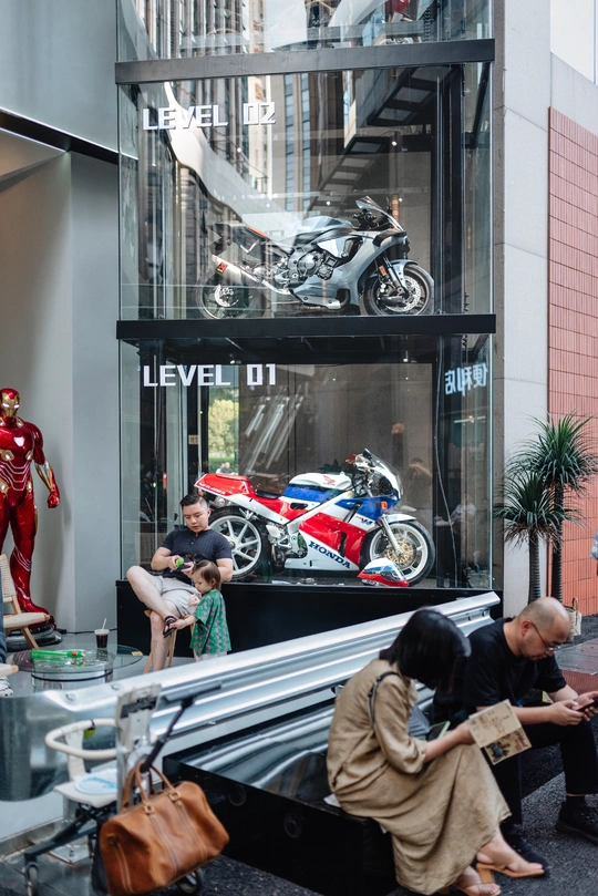 人们在建筑物外观看摩托车。