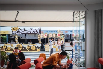 一个人坐在餐厅前面的窗户边的桌子旁