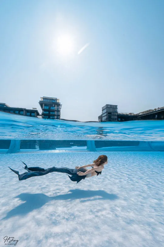 一个人在游泳池里 一个女孩在水面上方飞翔。