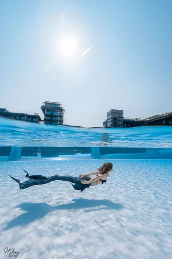一个人在游泳池里 一个女孩在水面上方飞翔。