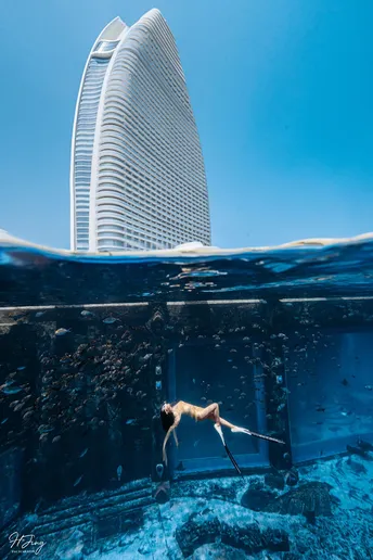 一位女性在游泳池中 背景是摩天大楼 水中有一栋像城市的建筑。