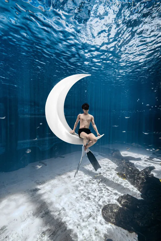 一个年轻人坐在水下的一把椅子上