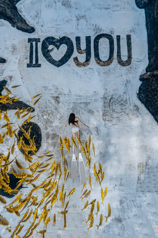 一位穿着连衣裙的女士站在一面墙上的壁画前