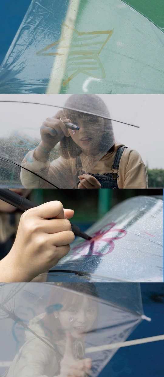 一个年轻女孩拿着雨伞透过汽车前挡风玻璃