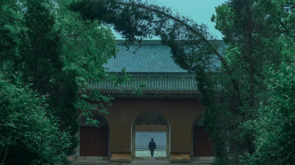 一个男人站在花园里的小路上 花园周围是树和建筑物