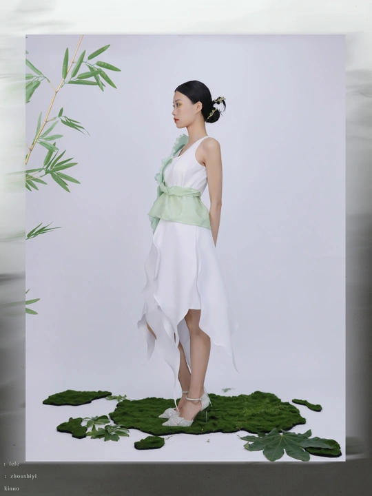 一位穿着白色连衣裙的年轻女子站在绿色背景前