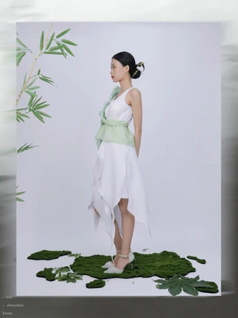 一位穿着白色连衣裙的年轻女子站在绿色背景前