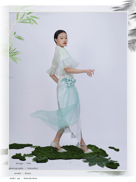 一位穿着蓝色连衣裙 裙子上饰有绿色叶子的模特