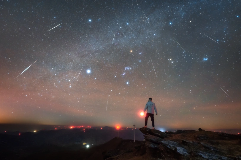 站在山顶上 仰望着夜空中星星的男子