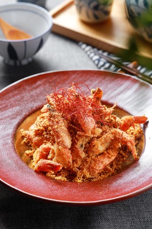 一碗食物旁边的一个红盘子 上面放着虾