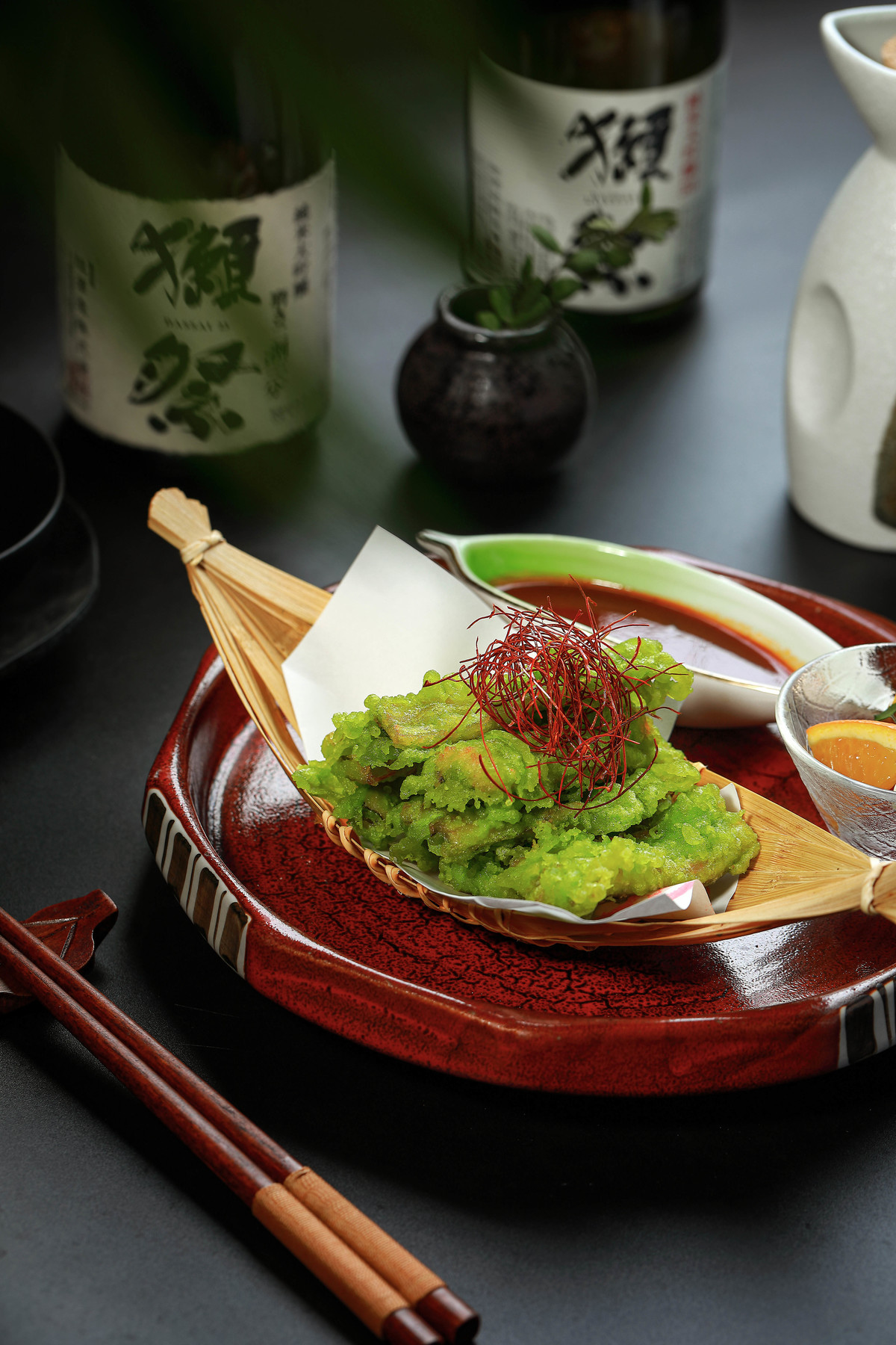 一小碗酱汁用筷子放在桌子上的红盘子上