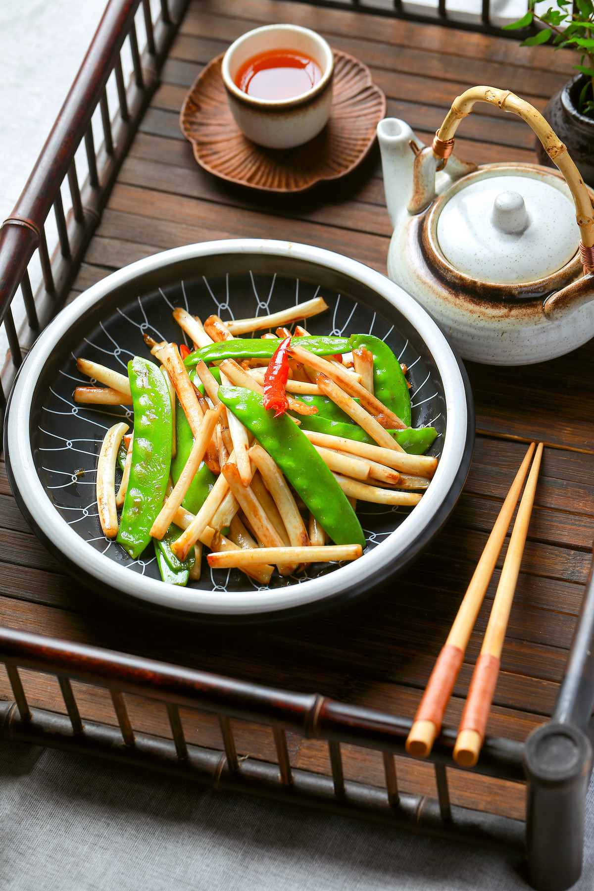 一张带有面条、蔬菜和一杯茶以及筷子的桌子