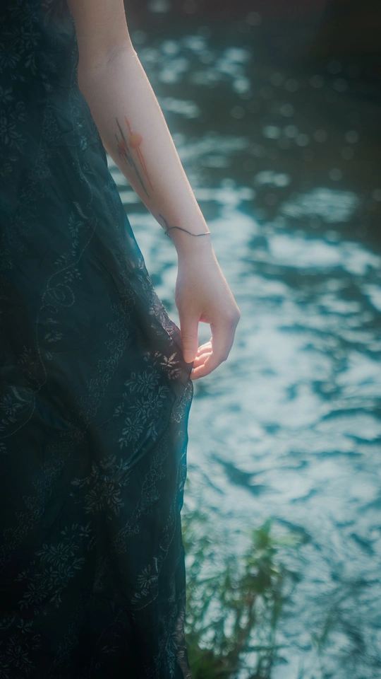 一个穿着黑色连衣裙的女人把手伸向一片水域
