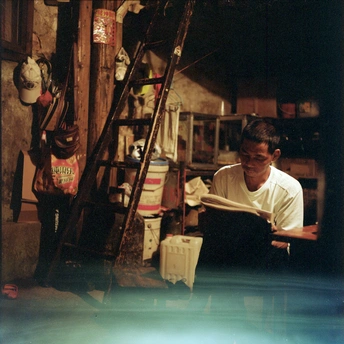 一个男人在房间里用笔记本电脑和一个正在看书的人