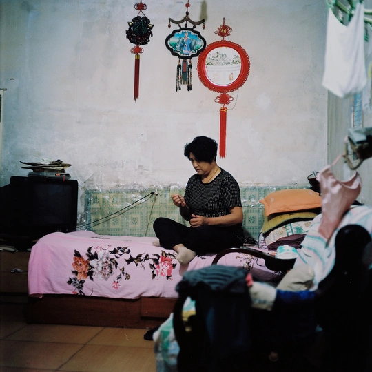 一个男人坐在小房间的床上 而一个女人坐在床上看手机