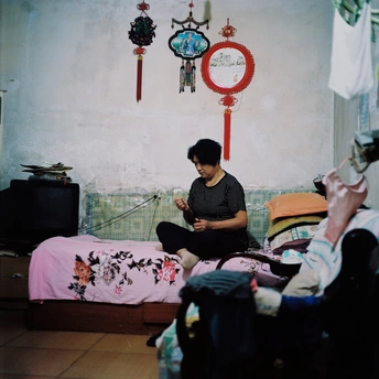 一个男人坐在小房间的床上 而一个女人坐在床上看手机