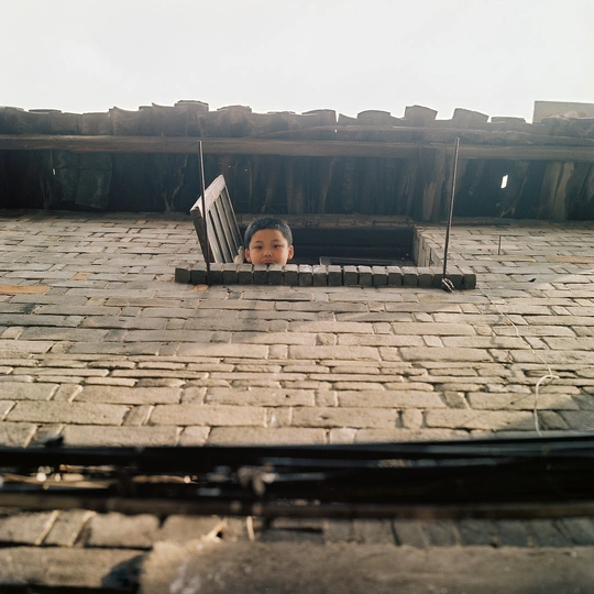 一个小孩从屋顶敞开的窗户向外看