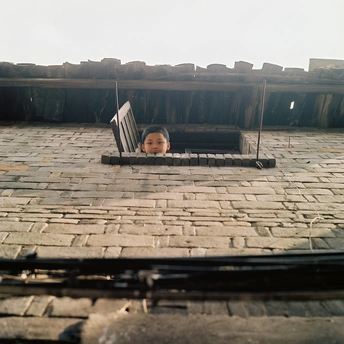 一个小孩从屋顶敞开的窗户向外看