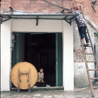 一座砖砌建筑 门开着 一个人在门前的梯子上爬椅子