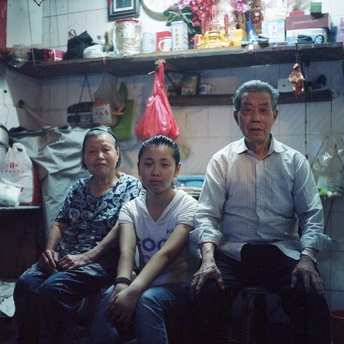 一家人坐在杂乱的厨房里 一名男子在房间中央的椅子上摆姿势