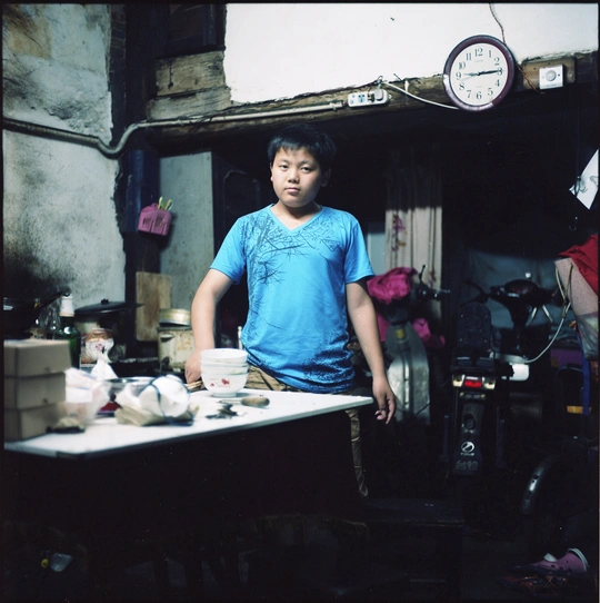 一个穿着蓝色衬衫的年轻人站在杂乱房间的柜台旁