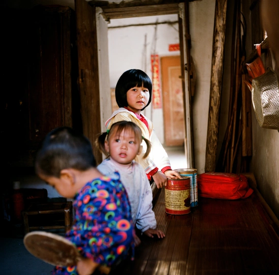 一对小男孩和小女孩站在一所小房子的走廊里