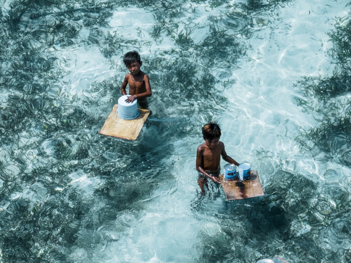 海上或海洋中一艘小船上的年轻男孩们嬉戏的水上视图
