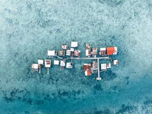 热带岛屿的空中视角 有小船和漂浮在蓝色水上的房子。