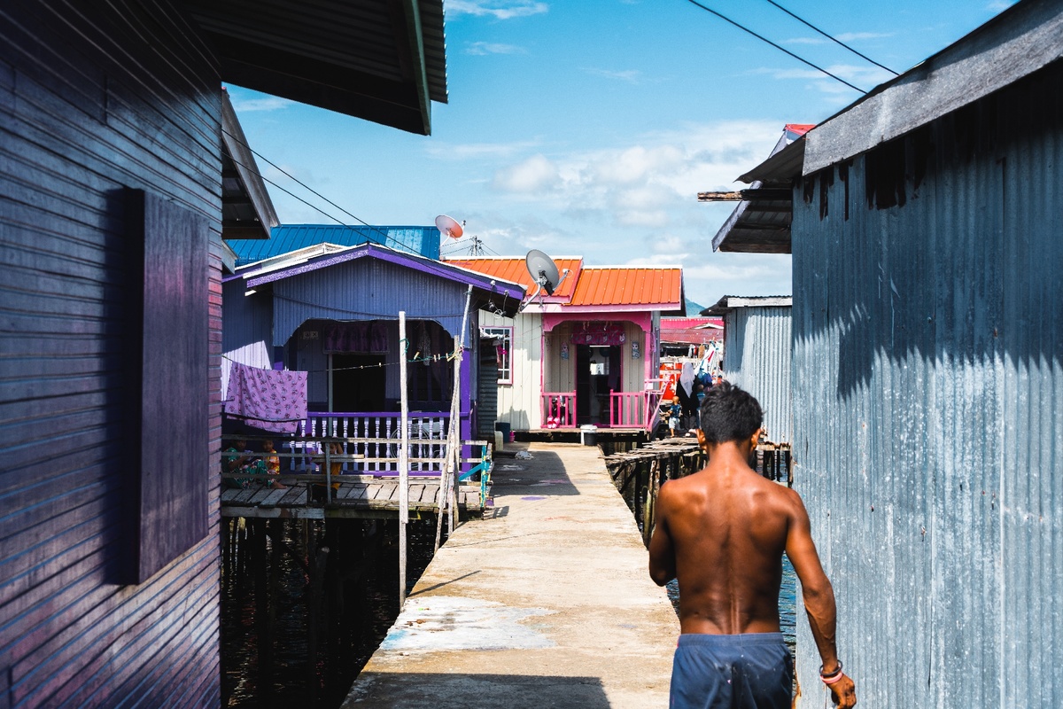 一个人走在一条沿着水边 色彩斑斓的房屋排列的街道上