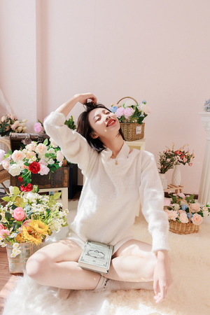 一个年轻女子坐在铺满鲜花的白房间里