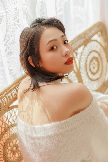 一位红发年轻女子坐在白色椅子前窗前