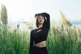 一位穿着黑色连衣裙的年轻女子在长草前摆姿势