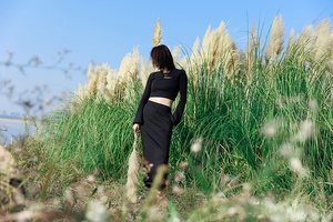一个穿黑色衣服的女人站在一片高草丛中