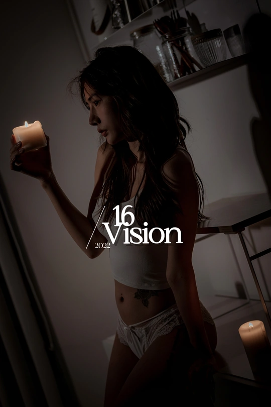 一个年轻女子手里拿着一支点燃的蜡烛 在一个光线昏暗的房间里。