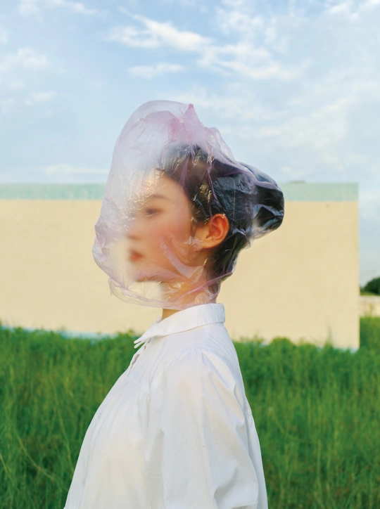 一个戴着塑料口罩的年轻女孩站在草地上