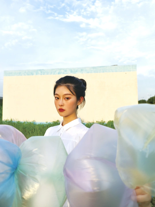 一个穿着白色连衣裙的年轻女子手里拿着一个蓝色气球的塑料袋