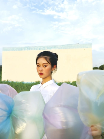 一个穿着白色连衣裙的年轻女子手里拿着一个蓝色气球的塑料袋