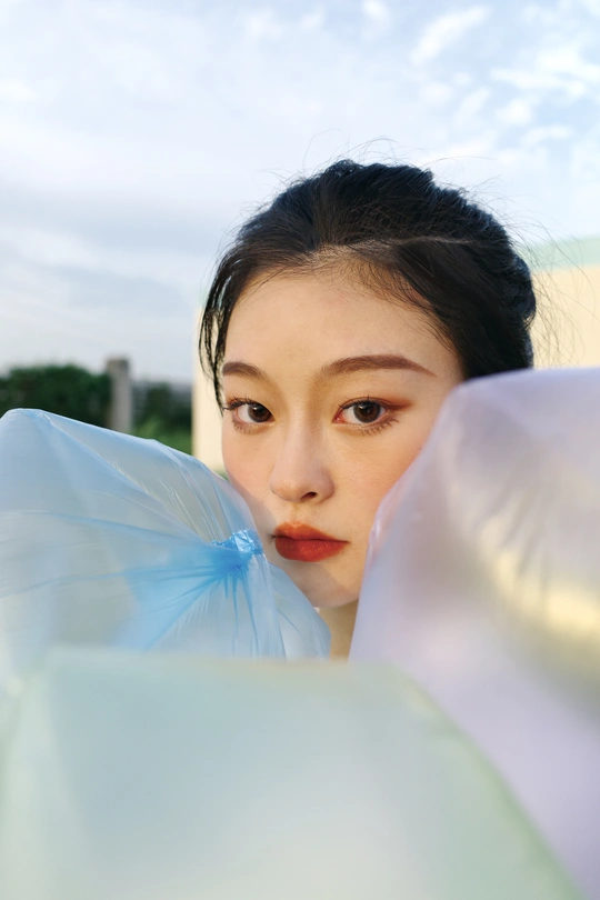 一位身穿蓝色连衣裙的年轻女子拿着一把塑料伞摆姿势